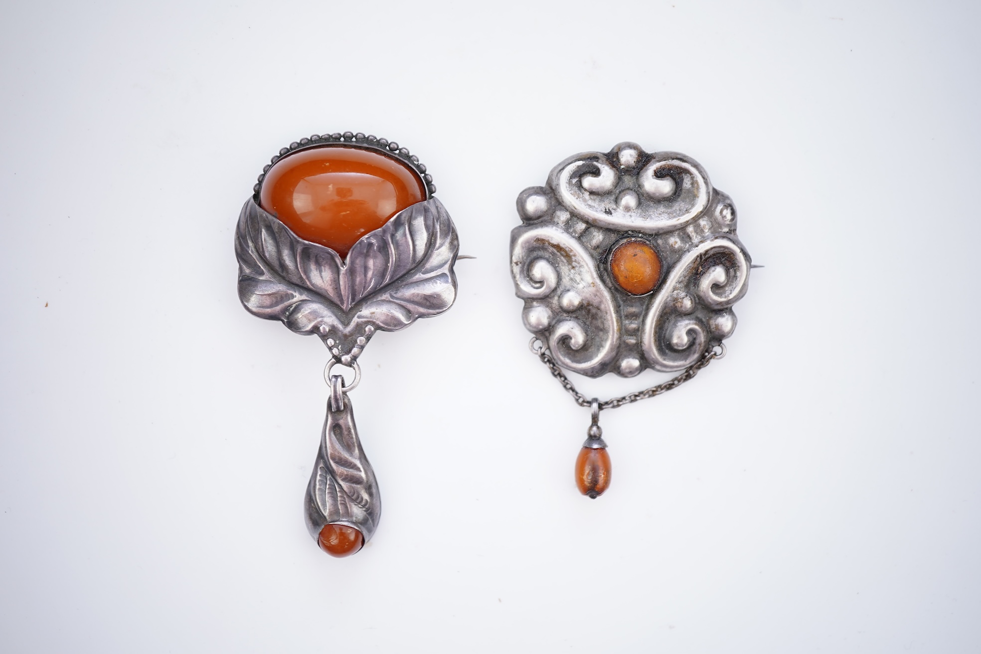 Two Arts & Crafts silver and amber pendant brooches, probably Denmark, early 20th century